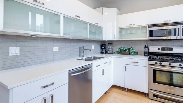 A modern kitchen with white cabinets, a stainless steel dishwasher, a double oven, and a microwave. - Beautiful Unit CHI in Prime River North - 2 (Chicago)