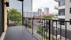 A balcony with a metal railing, a cityscape view, and a paved floor. - Beautiful Unit CHI in Prime River North - 2 (Chicago)