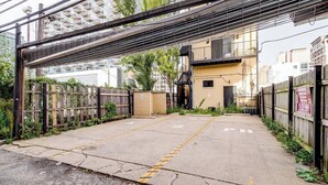An outdoor parking area with a concrete surface, yellow dashed lines, and a wooden fence. - Beautiful Unit CHI in Prime River North - 2 (Chicago)