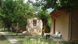 Ein friedlicher Garten mit einem Weg, der zu einem Gebäude mit einer kleinen Veranda und einer Sitzgelegenheit führt.