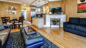A living room with a sofa, a coffee table, and a fireplace. There is a television mounted above the fireplace. - Historic and Unique Brownstone in Gold Coast - 3 (Chicago)