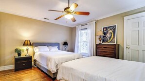A bedroom with two beds, a ceiling fan, a nightstand with a lamp, a dresser, and a window with curtains. - Historic and Unique Brownstone in Gold Coast - 3 (Chicago)