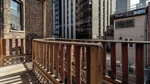 A balcony with wooden railings overlooking a cityscape with tall buildings. - Historic and Unique Brownstone in Gold Coast - 3 (Chicago)