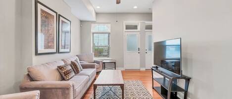 A modern living room with a sofa, coffee table, TV, and ceiling fan.
