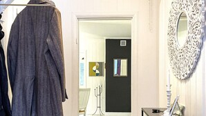 A hallway with a coat rack, a black door with a small window, and a mirror on the wall. - 2 Person Holiday Home in Aby (Aby)