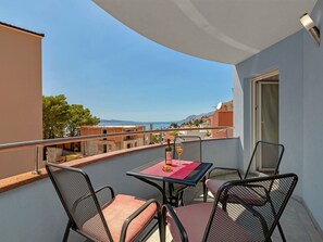 A balcony with a table and chairs, overlooking a scenic view of the sea and mountains. - Apartments Villa Juric - One-bedroom Apartment - 2 (Baska Voda)