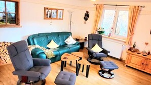 Un salón acogedor con un sofá azul, dos sillones, una mesita de centro y un mueble de madera.