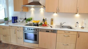 Una cocina moderna con electrodomésticos de acero inoxidable, armarios de madera y una isla central con verduras frescas.