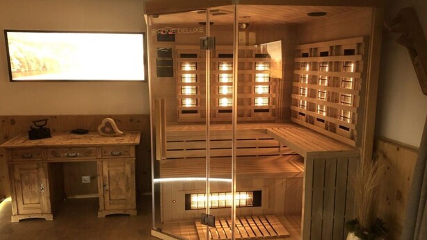 A sauna room with wooden benches and a glass partition. - Chalet Bernegg - Otztal (Sautens)