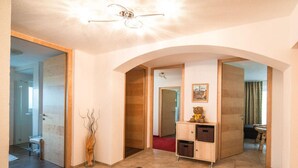A spacious hallway with a tiled floor, a wooden cabinet with drawers, and a framed picture on the wall. - Chalet Bernegg - Otztal (Sautens)