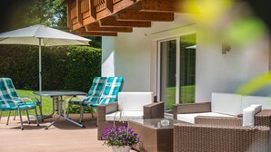 An outdoor patio with wicker furniture, a table, and chairs, and a white umbrella. - Chalet Bernegg - Otztal (Sautens)