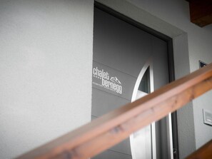 L’entrée d’un immeuble d’appartements moderne, avec le logo de « Chalet Bernegg » et une rampe d’escalier en bois.