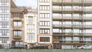 A multi-story building with balconies, a sign reading "Villa Robert," and a fenced area with parked cars and bicycles. - Seafront Apartment Close to the Casino (Blankenberge)