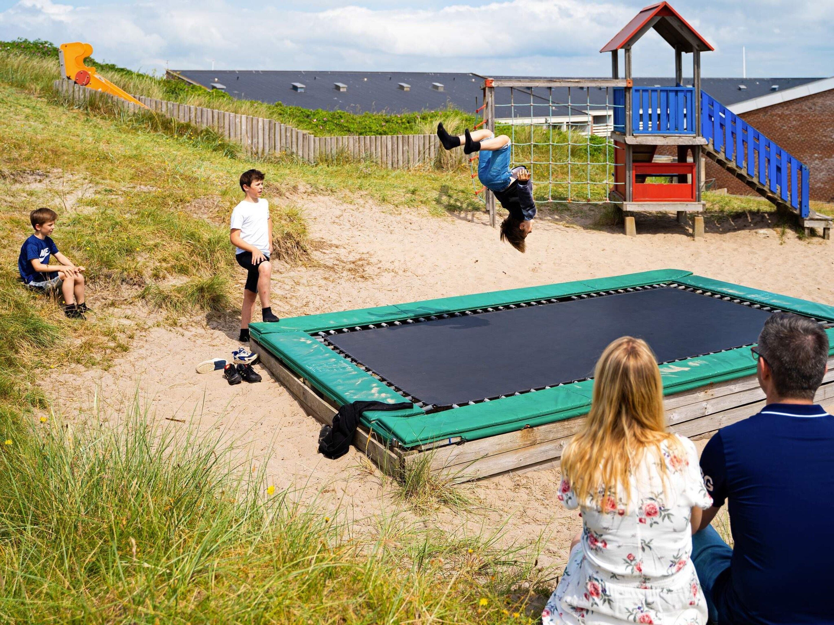 A beach with a trampoline, a wooden fence, and a lifeguard tower.