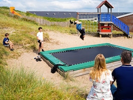 A beach with a trampoline, a wooden fence, and a lifeguard tower.