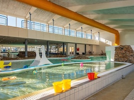 Una piscina interior con techo alto, agua cristalina y pared de piedra.