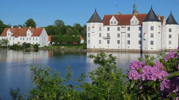 A large white building with multiple towers and a red roof, situated by a calm body of water. - Diekkier Modern Retreat (Dollerup)
