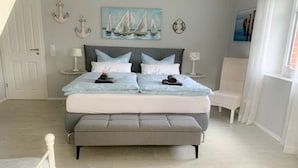 A bedroom with a large bed, two bedside tables, a chair, and a painting of sailboats on the wall. - Diekkier Modern Retreat (Dollerup)