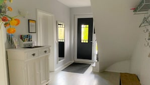 A hallway with a white cabinet, a door with a window, and a bench. - Diekkier Modern Retreat (Dollerup)