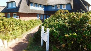 Un bâtiment traditionnel avec un toit de chaume, de nombreuses fenêtres et un chemin qui y mène.