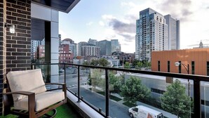 Een balkon met uitzicht op een stadsbeeld, een bakstenen muur en een moderne stoel.
