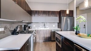 Een moderne keuken met donkerhouten kasten, roestvrijstalen apparatuur en een wit aanrecht.