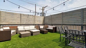 A patio with wicker furniture, a metal bench, and a string of lights. - Downtown Goose Island with access to patio - 1 (Chicago)