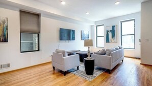 A modern living room with a grey sofa set, a coffee table, and a flat-screen TV mounted on the wall. - Downtown Goose Island with access to patio - 1 (Chicago)
