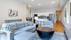 A modern living room with a grey sofa, a black coffee table, and a kitchen in the background. - Downtown Goose Island with access to patio - 1 (Chicago)