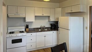 A kitchen with white cabinets, a stove, a sink, and a refrigerator. - Close to Downtown - 2 queen beds (Springfield)