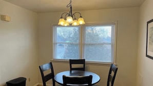 A dining area with a round table and four chairs, a chandelier, and a window with blinds. - Close to Downtown - 2 queen beds (Springfield)