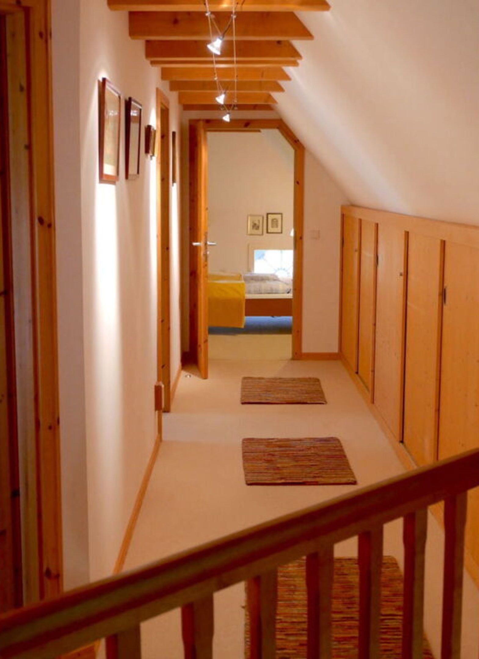 A narrow hallway with wooden beams on the ceiling and a staircase at the end.