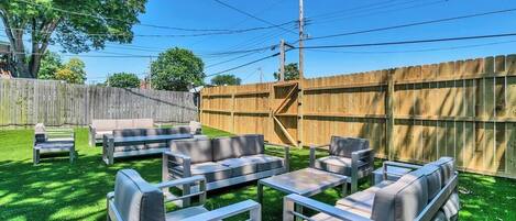 A backyard with outdoor furniture, a wooden fence, and a tree.