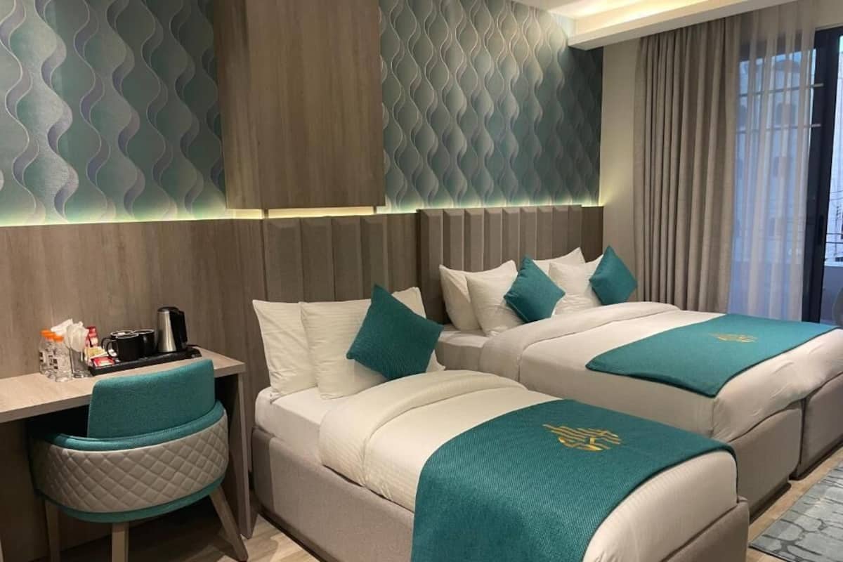 A hotel room with two beds, a desk, and a chair.