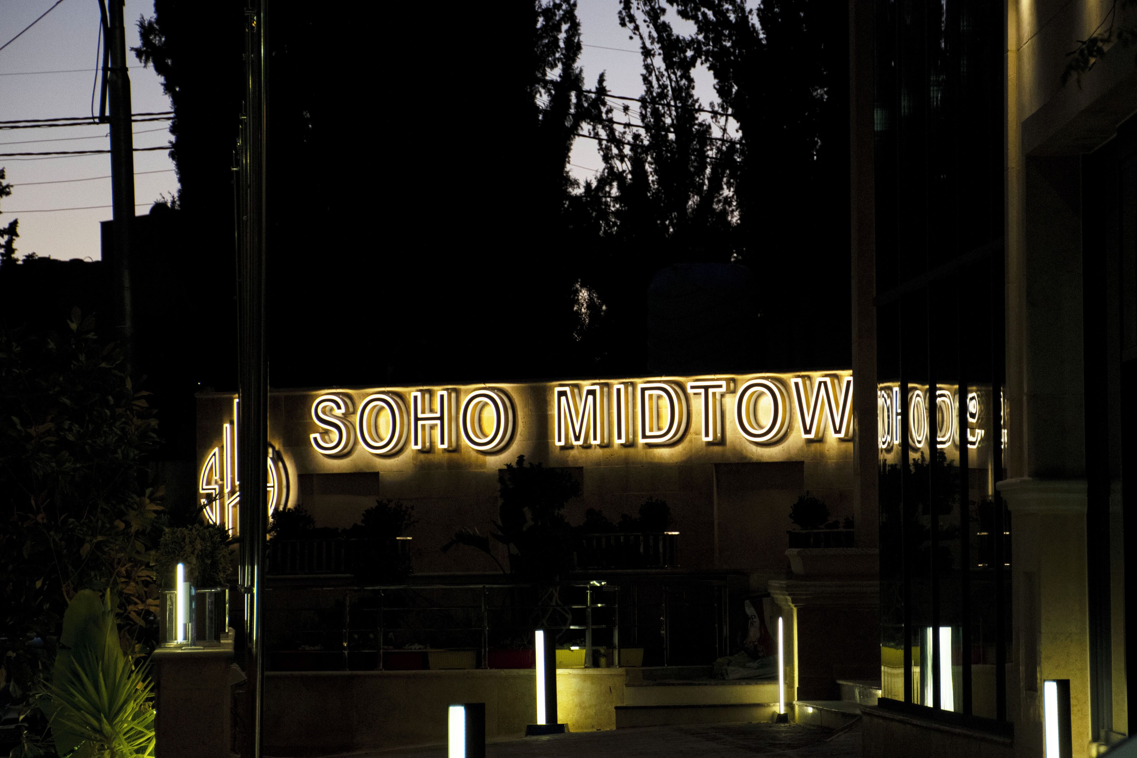 The entrance to Soho Midtown Hotel with illuminated signage.