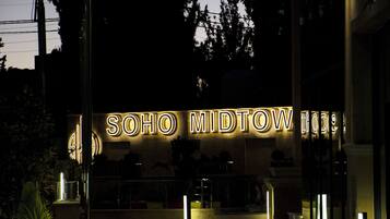 The entrance to Soho Midtown Hotel with illuminated signage.