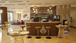 A modern bar area with a counter, stools, and a coffee machine. - Soho Midtown Hotel (Amman)