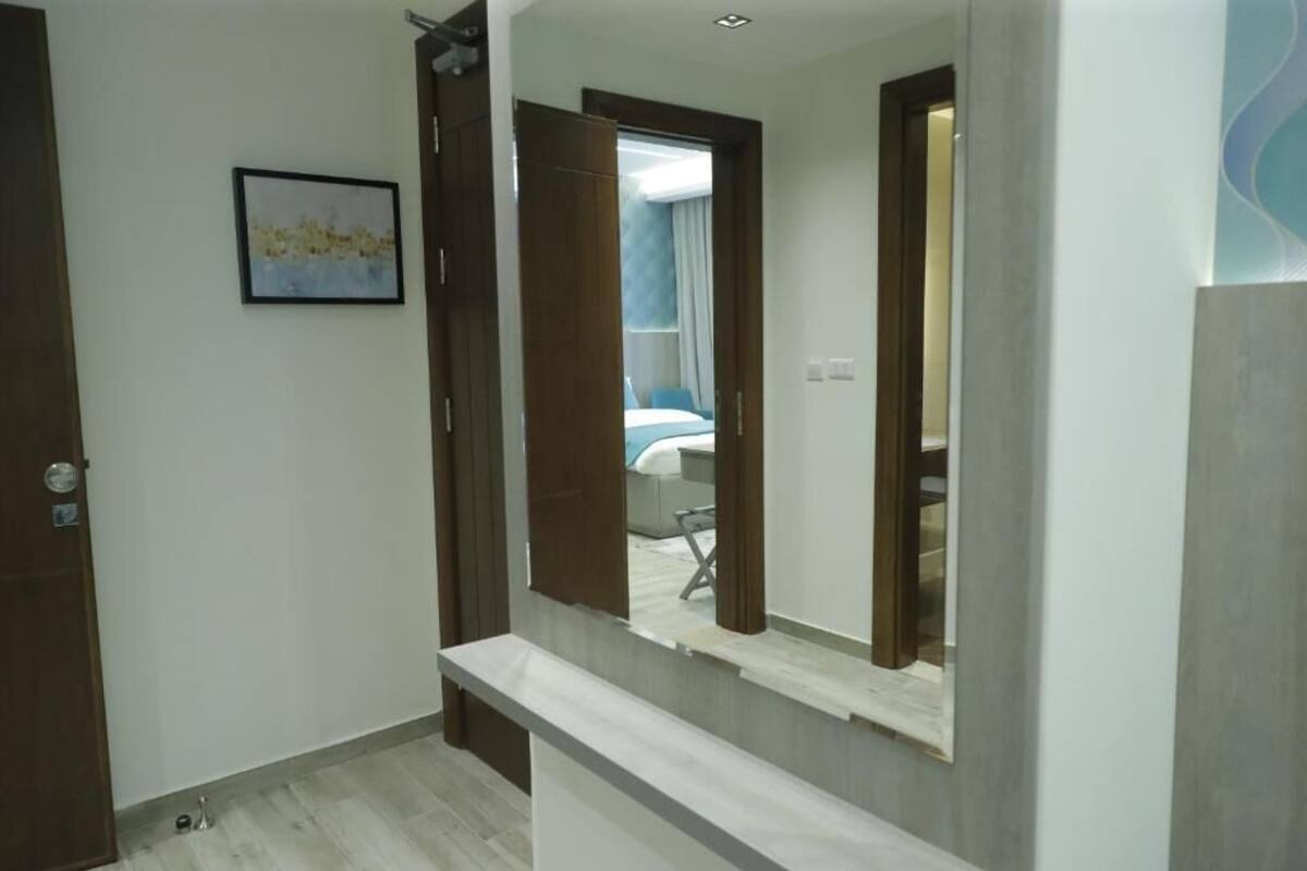 A hotel room with a large mirror, a bed, and a small desk.