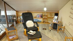 A cozy reading nook with a black chair, a small wooden table, and a floor lamp. - Holiday Apartment Magnolia (Ockfen)