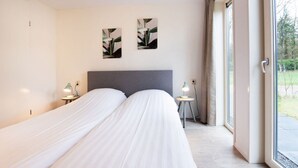 A modern hotel room with two beds, a large window, and two wall-mounted artworks.