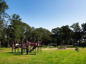 Children can play on swings, a slide, and climbing structures in this park area.