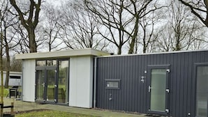 A modern building with a flat roof, large glass doors, and a dark exterior.