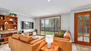 Una sala de estar moderna con un sofá de cuero, una mesita de madera y un televisor.