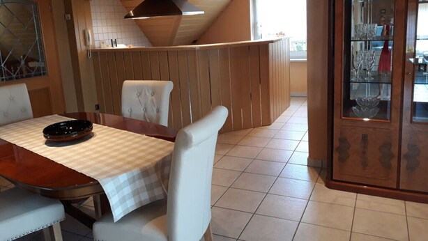 A dining area with a wooden table, white upholstered chairs, and a glass cabinet with decorative items. - Also a Modern Retreat (Röbel/Müritz)