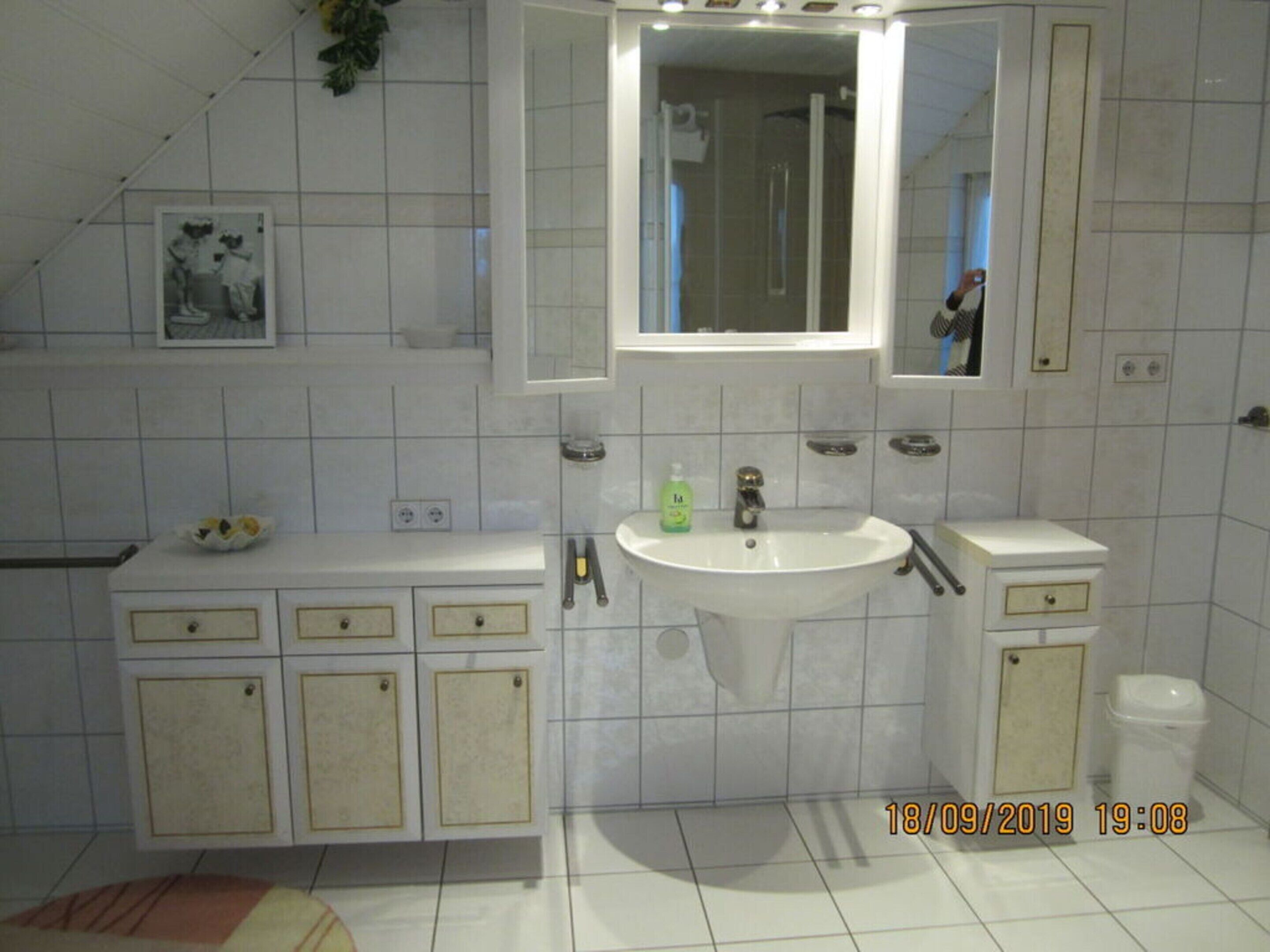 A bathroom with a sink, mirror, cabinets, and a shower area.