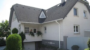 A two-story house with a tiled roof, a garage, and a fenced yard. - Also a Modern Retreat (Röbel/Müritz)