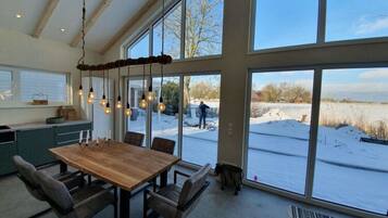 A spacious dining area with a wooden table and chairs, large windows offering a view of a snowy landscape.