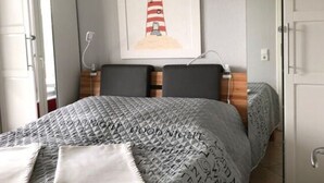 A hotel room with a bed, a nightstand, a lamp, a framed welcome sign, and a wardrobe. - Apartment Near the Beach With sun Balcony (Boltenhagen)
