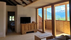 Una habitación con un armario de madera, un televisor y un amplio ventanal corredera con vistas panorámicas.