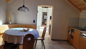 Un comedor con una mesa redonda, bancos y una lámpara colgante.